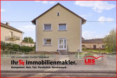 Freistehendes Einfamilienhaus mit sonnigem Garten, Nebengebäude und Garage.